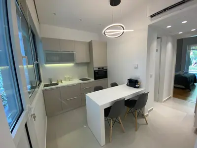 a kitchen with a white counter and some chairs at Fospitality Varkiza in Varkiza
