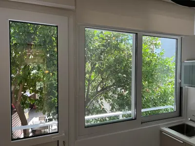 two windows in a kitchen looking out at a tree at Fospitality Varkiza in Varkiza