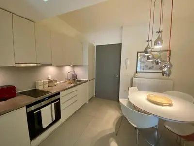 a white kitchen with a table and chairs in it at Fospitality Varkiza in Varkiza