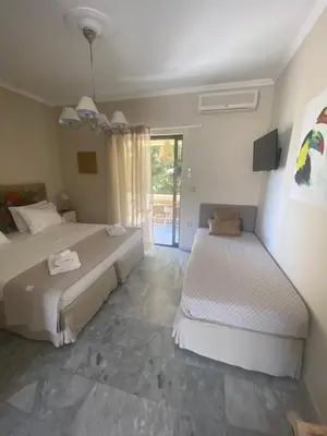 a bedroom with two beds and a sliding glass door at Aelia Houses in Agia Marina Aegina