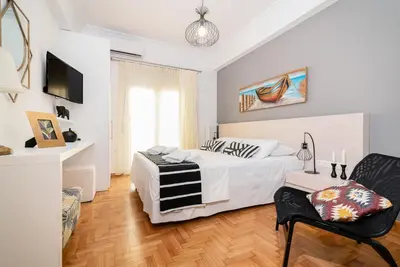 a white bedroom with a bed and a chair at Lyto by Heloni Apartments in Athens
