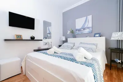 a white bedroom with a bed with a tv on the wall at Lyto by Heloni Apartments in Athens