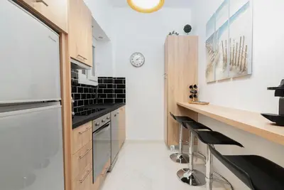 a kitchen with white walls and wooden cabinets and black appliances at Lyto by Heloni Apartments in Athens