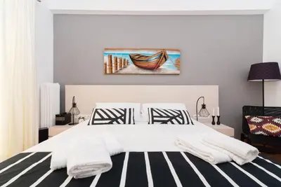 a bedroom with a bed and a painting of a boat at Lyto by Heloni Apartments in Athens