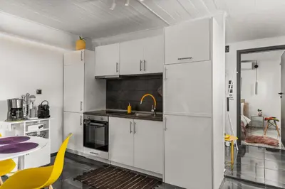 a kitchen with white cabinets and a table and yellow chairs at Luxe house in Glyfada with spa near metro station C8 in Athens