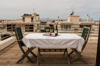 a table with wine bottles and glasses on a roof at Family getaway, spacious and luxurious, sea view, terrace, 5 minutes from Voula beach, 30min from Athens center in Athens