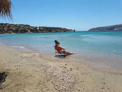 a woman sitting in a chair on the beach at Family getaway, spacious and luxurious, sea view, terrace, 5 minutes from Voula beach, 30min from Athens center in Athens