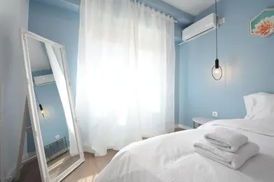 a bedroom with a white bed and a mirror at 3 mins walking from Acropolis in Athens