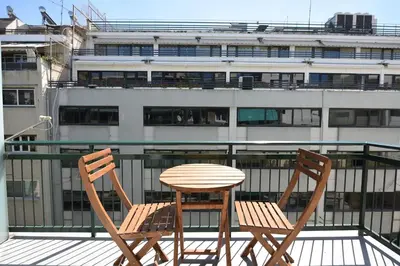 two chairs and a table on a balcony with a building at 3 mins walking from Acropolis in Athens