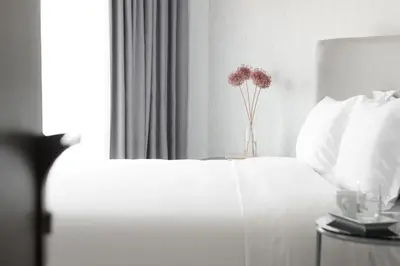 a white bed with a vase of flowers on it at Athens Utopia Ermou in Athens
