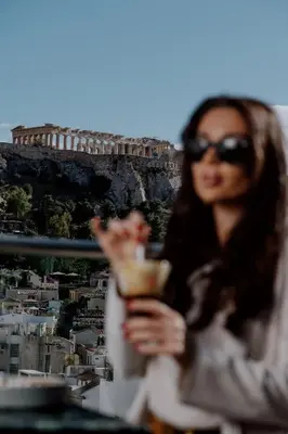 a woman in sunglasses holding a drink in front of the coliseum at Athens Utopia Ermou in Athens