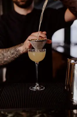 a man pouring a drink into a martini glass at Athens Utopia Ermou in Athens