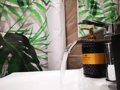 a bottle of soap sitting next to a bathroom faucet at Sea&Sun Glyfada Apartment in Athens
