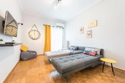 a living room with a couch and a clock on the wall at Gorgeous & Modern At Ampelokipi Metro Station By Greece Apartments in Athens