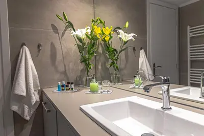 a bathroom with a sink and flowers in a mirror at Marveco Apartment in Athens