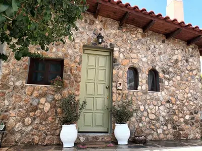 a stone building with a green door and two white vases at Garden's House in Spáta