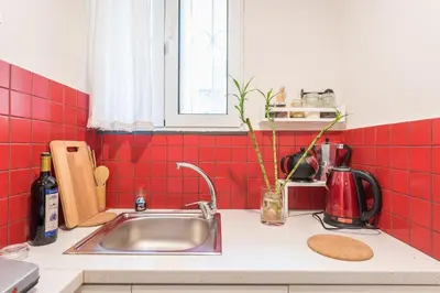a kitchen counter with a sink and red tiles at Cozy studio 5mins walk from Acropolis museum in Athens