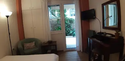a hotel room with a bed and a chair and a window at Cozy studio 5mins walk from Acropolis museum in Athens