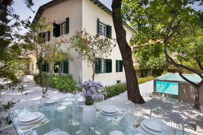 a table with plates and flowers on it in front of a house at Glyfada Villa 6BR 16ppl Private Pool 300m to Beach in Athens