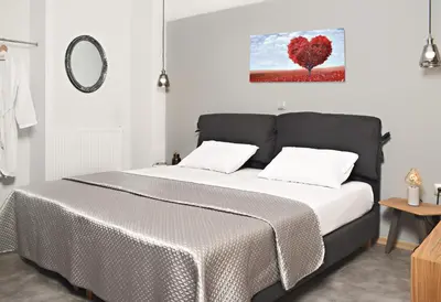 a bed in a room with a red heart painting on the wall at BEAUTIFUL PEOPLE SUITES ATHENS ACROPOLIS VIEW in Athens
