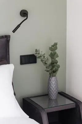 a vase with a plant on a table next to a bed at 12 Reasons Why Metaxourgeio in Athens