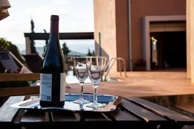 a bottle of wine and two glasses on a table at Villa Rosa with private pool, Athens Riviera in Kalívia Thorikoú