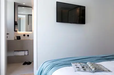 a bedroom with a bed with a tv on the wall at The Alex Monte Kastella, Santikos Collection in Piraeus