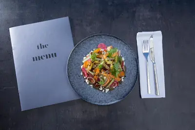 a plate of food on a table next to a napkin at The Alex Monte Kastella, Santikos Collection in Piraeus