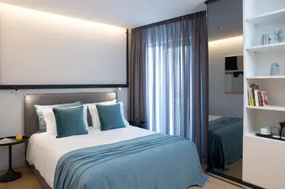 a bedroom with a large bed with blue pillows at The Alex Monte Kastella, Santikos Collection in Piraeus