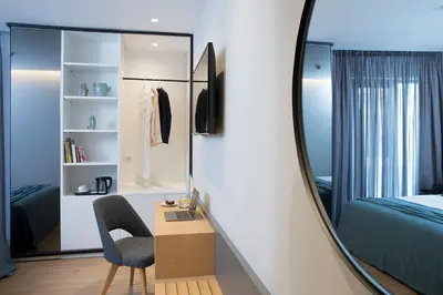 a bedroom with a mirror and a chair and a desk at The Alex Monte Kastella, Santikos Collection in Piraeus