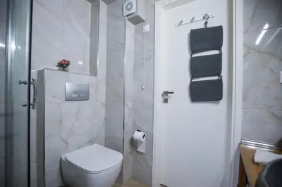 a white bathroom with a toilet and a shower at Rastoni Athens Suites near Acropolis at Tsatsou street in Athens