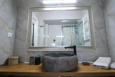 a bathroom with a large mirror and a stone sink at Rastoni Athens Suites near Acropolis at Tsatsou street in Athens
