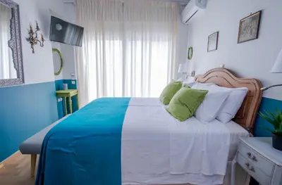 a blue and white bedroom with a bed with white and green pillows at Rastoni Athens Suites near Acropolis at Tsatsou street in Athens