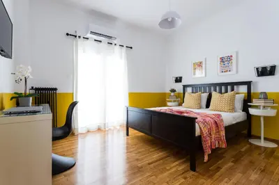 a bedroom with a bed with yellow and white walls at Urban Athens Apartment in Athens