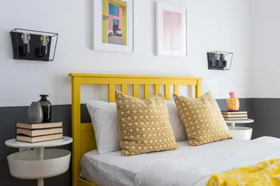 a bedroom with a yellow bed with pillows and books at Urban Athens Apartment in Athens