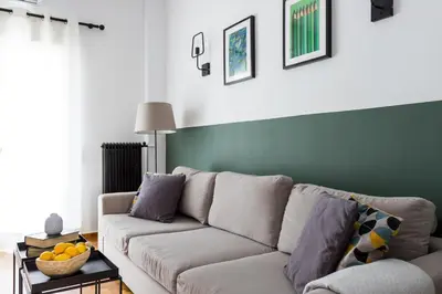 a living room with a couch and a green wall at Urban Athens Apartment in Athens