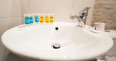 a white bathroom sink with four bottles on it at Athens Psiri Hotel in Athens