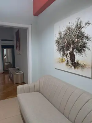 a living room with a couch and a tree on the wall at Paradise apartment in Koukaki in Athens