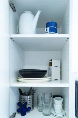 a white pantry with dishes and plates on shelves at Small & cozy with Acropolis & Lycabettus view in Athens