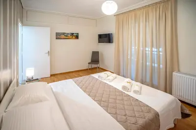 a bedroom with a large white bed and a window at Leo's home in Athens