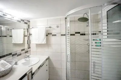 a white bathroom with a shower and a sink at Leo's home in Athens