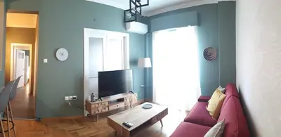 a living room with a red couch and a tv at Kanigos 3 BR VIEW Center of Athens in Athens