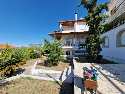 a large white building with flowers in front of it at The Mirador Boutique Villa with Scenic Sea View in Porto Rafti