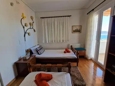a bedroom with two beds and a window with the ocean at The Mirador Boutique Villa with Scenic Sea View in Porto Rafti