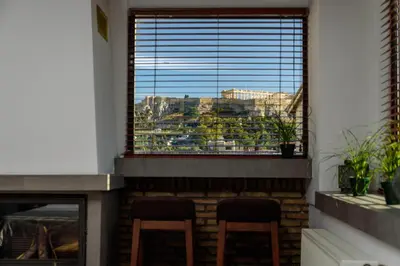 a fireplace with two chairs in front of a window at Acropolis Eye Loft in Athens