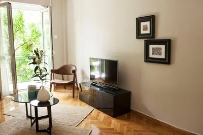 a living room with a tv and a chair at Chic & Comfortable Central Apart, close to National Archeological Museum! in Athens