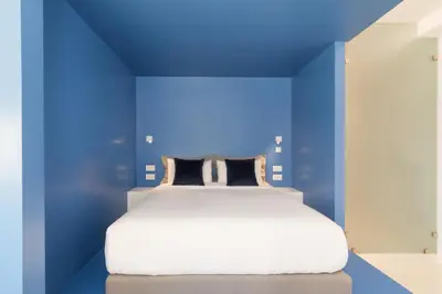 a blue bedroom with a white bed and a blue wall at Athens Color Cube in Athens