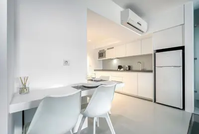a white kitchen with a white desk and chairs at Athens Color Cube in Athens
