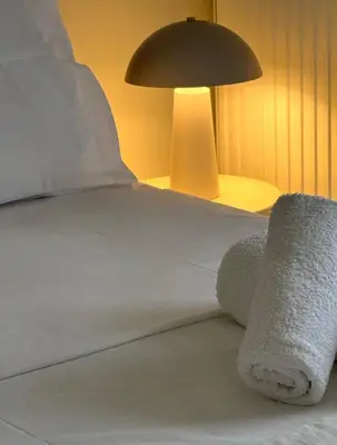 a bed with white towels on it with a lamp at Kalliopi's apartment in Athens