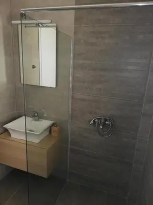 a bathroom with a shower with a sink and a mirror at Comfortable Apartment Close to the Airport in Spáta